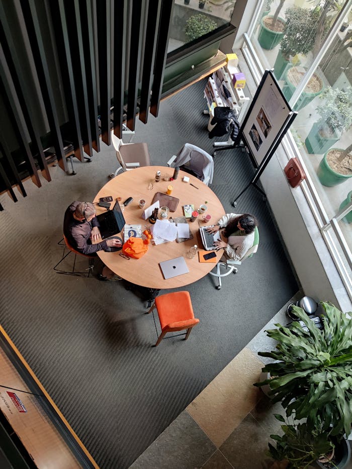 gallery-6 Top view of professionals collaborating in a modern Gurugram office with laptops and coffee.